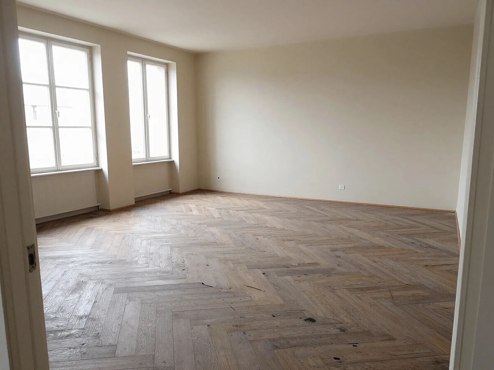 Salon avant rénovation : parquet en chevrons usé.