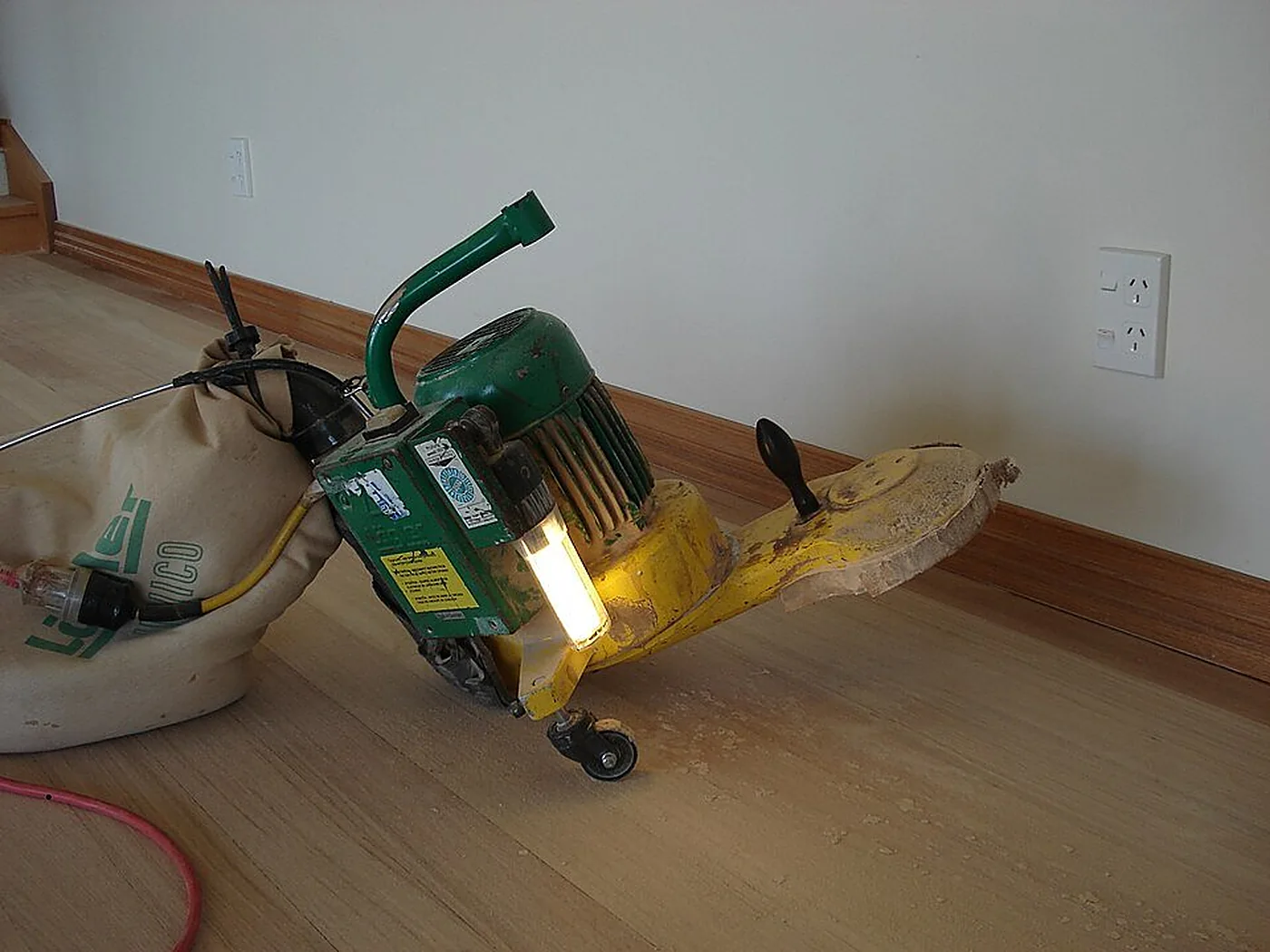 Bordureuse verte au pied d’une plinthe, sur un parquet clair.